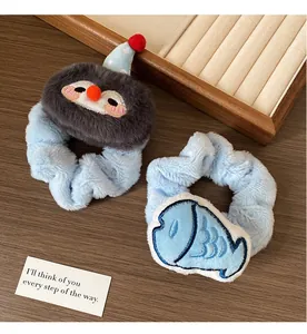 Detailed view of plush penguin and blue fish cartoon hair scrunchies on wooden background
