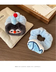 Detail of plush penguin scrunchies and blue fish hair ties on a wooden surface