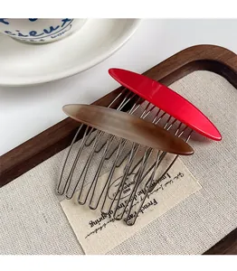 Modern acetate hair side comb set in red and amber brown on a wooden tray with linen