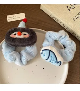 Detail of plush cartoon scrunchie set with blue penguin and fish on a white ceramic plate