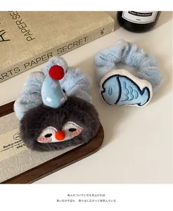 Detail of plush blue hair scrunchies featuring cute 3D penguin and fish embroidery