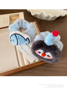 Detail of plush penguin and fish scrunchies in a wooden tray with cozy textures