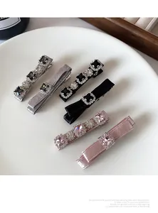 Detailed set of 6 crystal bow hair clips in black, pink and grey on a white plate