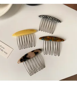 Dettaglio di quattro pettini per capelli in acetato con denti in metallo e marchio artigianale