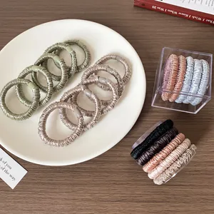 Elegant satin hair scrunchies set in Morandi tones displayed on a minimalist wooden table