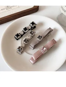Detailed view of four satin bow hair clips with crystals on a white porcelain plate