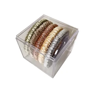 Set of satin silk scrunchies in metallic colors inside a transparent acrylic box