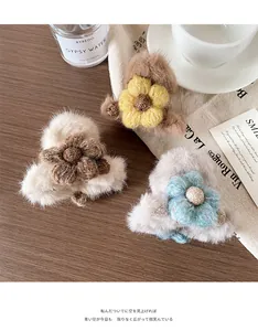 Detailopname van drie pluche bloemvormige haarklemmen in beige, bruine en grijze tinten