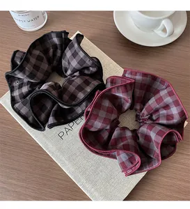 Close-up of grey and burgundy plaid fabric scrunchies on a dark wooden background