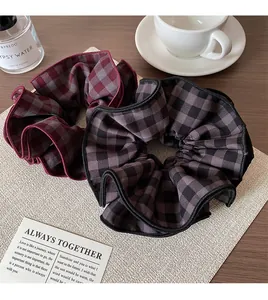 Close-up of red and black plaid scrunchies with pleated fabric texture on a mat