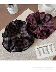 Detail of red and black checkered scrunchies with pleated fabric texture on a desk