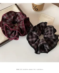 Close-up of oversized plaid scrunchies in wine red and black with thick wavy fabric edges