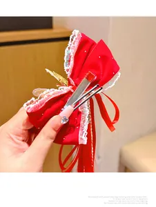 Detail of red velvet bow hair clip with white lace trim and long flowing tassels