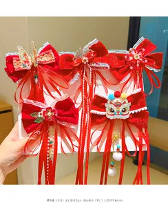 Close-up of red velvet hair bows with Chinese lion embroidery and pearl tassels