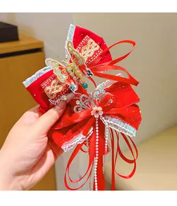 Detail of red velvet bow hairclip with golden butterfly embroidery and pearl tassels