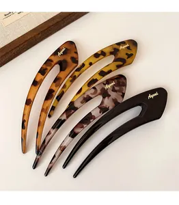 Close-up of four U-shaped hairpins with leopard print, tortoiseshell patterns, and gold logos