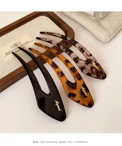 Detailed view of three U-shaped hairpins in black and tortoiseshell with gold logo