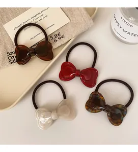 Detail of four acetate bow hair ties in tortoise, brown, white and red colors