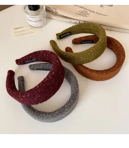 Detail of four multi-color thick tweed headbands with golden glitter and handmade labels