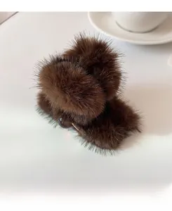 Detail einer plüschigen braunen Haarklammer auf einer minimalistischen weißen Tischfläche