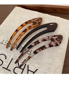 Close-up of three U-shaped hair pins in leopard, black, and marble textures with gold logos
