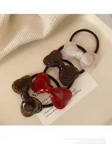 Close-up of four assorted colorful resin bow hair ties on a cream tray background