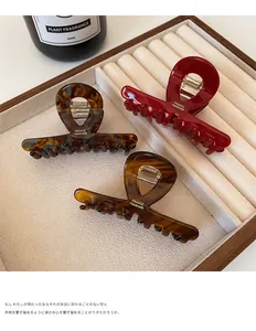 Three-piece acetate hair claw clips set in tortoise shell and amber on a beige tray
