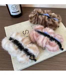 Detailopname van pluche banaan haarclips in bruin, roze en beige met zachte bontballen