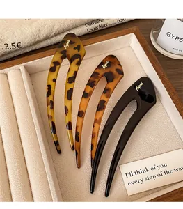 Detail of three U-shaped hairpins with leopard print and black finish on a velvet tray