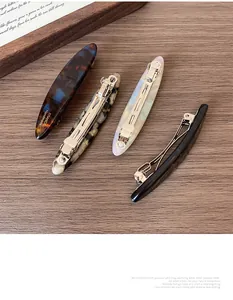 Detail of four vintage acetate spring hair clips on a natural rustic wood background