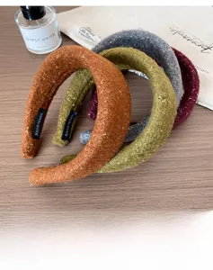 Detailed view of four thick sequined wool headbands with handmade labels on a wooden table