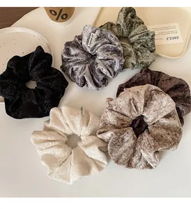 Detailed view of plush velvet scrunchies in various solid colors on a table