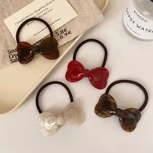 Elegant 4-piece set of glossy bow hair ties in multiple colors on a beige tray