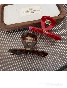 Detail of red and tortoiseshell acetate hair claws with gold springs and handmade logo