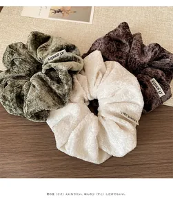 Detailed view of three plush faux fur scrunchies in green, white, and brown colors