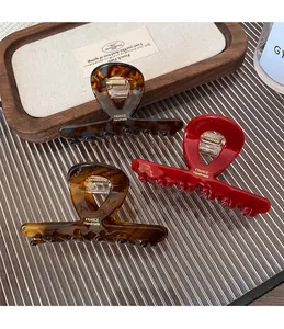Detail showing high-gloss acetate hair claws in tortoise shell and vibrant red finishes