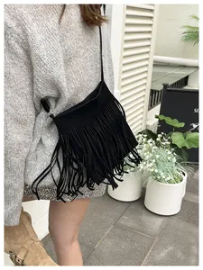 Close-up of black suede crossbody bag with long fringes in a street style setting
