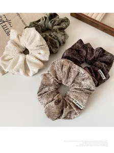 Detailed view of four plush velvet scrunchies in cream green and brown tones