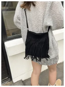 Detailed view of a black fringe crossbody bag with soft suede texture on a model