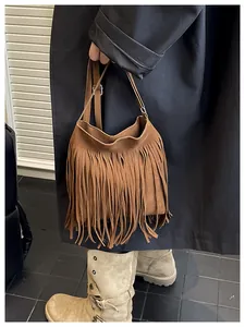 Detail of brown suede shoulder bag with fringe tassel design worn with dark coat