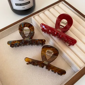 Three large acetate hair claws in dark red, tortoiseshell, and amber on a jewelry tray