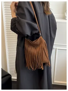 Detail of a brown suede crossbody bag with vintage long fringe tassels and a slim shoulder strap