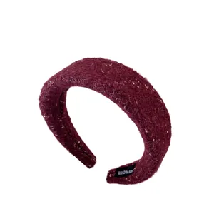 Padded burgundy wool headband with sequins and handmade label on white background