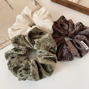 Three-piece plush scrunchie set in cream, olive green, and dark brown chenille fabric