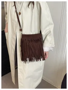 Detail of brown faux suede crossbody bag with long tassels and silver metal buckle