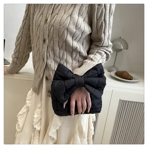 Detail of a chic black quilted handbag shaped like an oversized bow with nylon texture