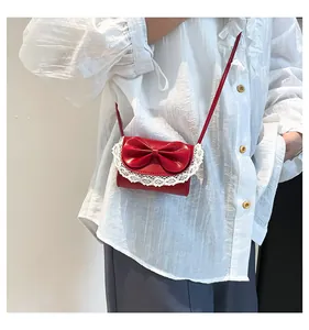 Primer plano del mini bolso rojo con encaje y lazo llevado por una modelo