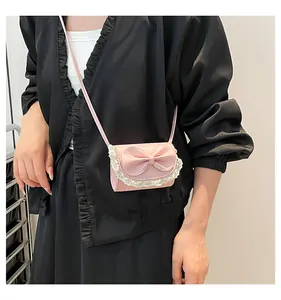 Vista detallada del mini bolso bandolera rosa con lazo grande y ribete de encaje blanco