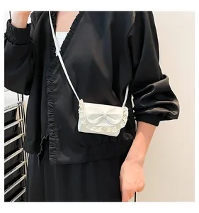 Détail du mini sac blanc perle avec bordure en dentelle et nœud papillon en relief