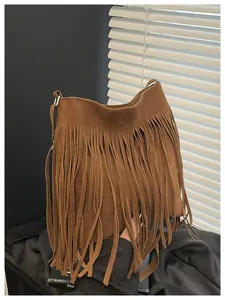 Detail of dark brown suede crossbody bag featuring long bohemian tassels and silver hardware